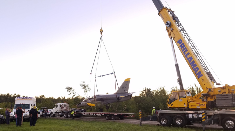 A crane is lifting an airplane onto the trailer.
