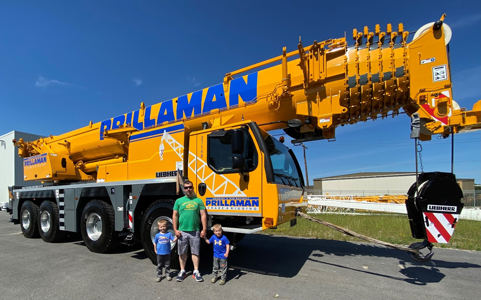 A man and two boys standing in front of a large crane.