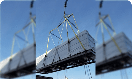 A crane lifting a large stack of white tiles.