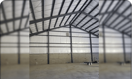 A large warehouse with metal beams and concrete floors.