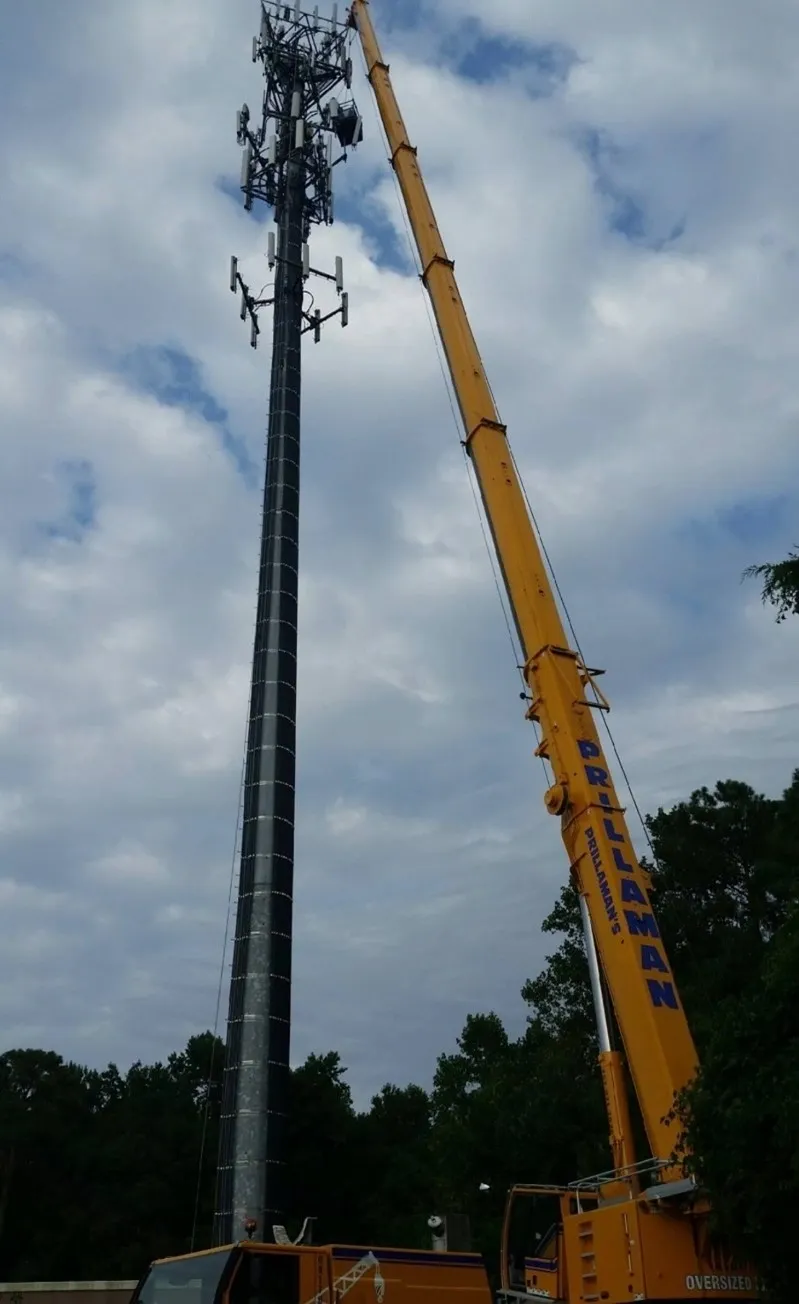 A crane is lifting up the top of a pole.