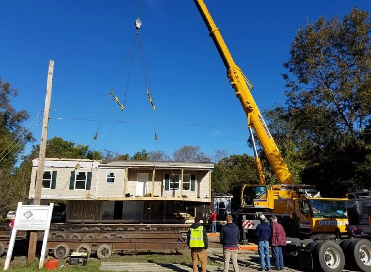 A crane is lifting up the roof of a house.