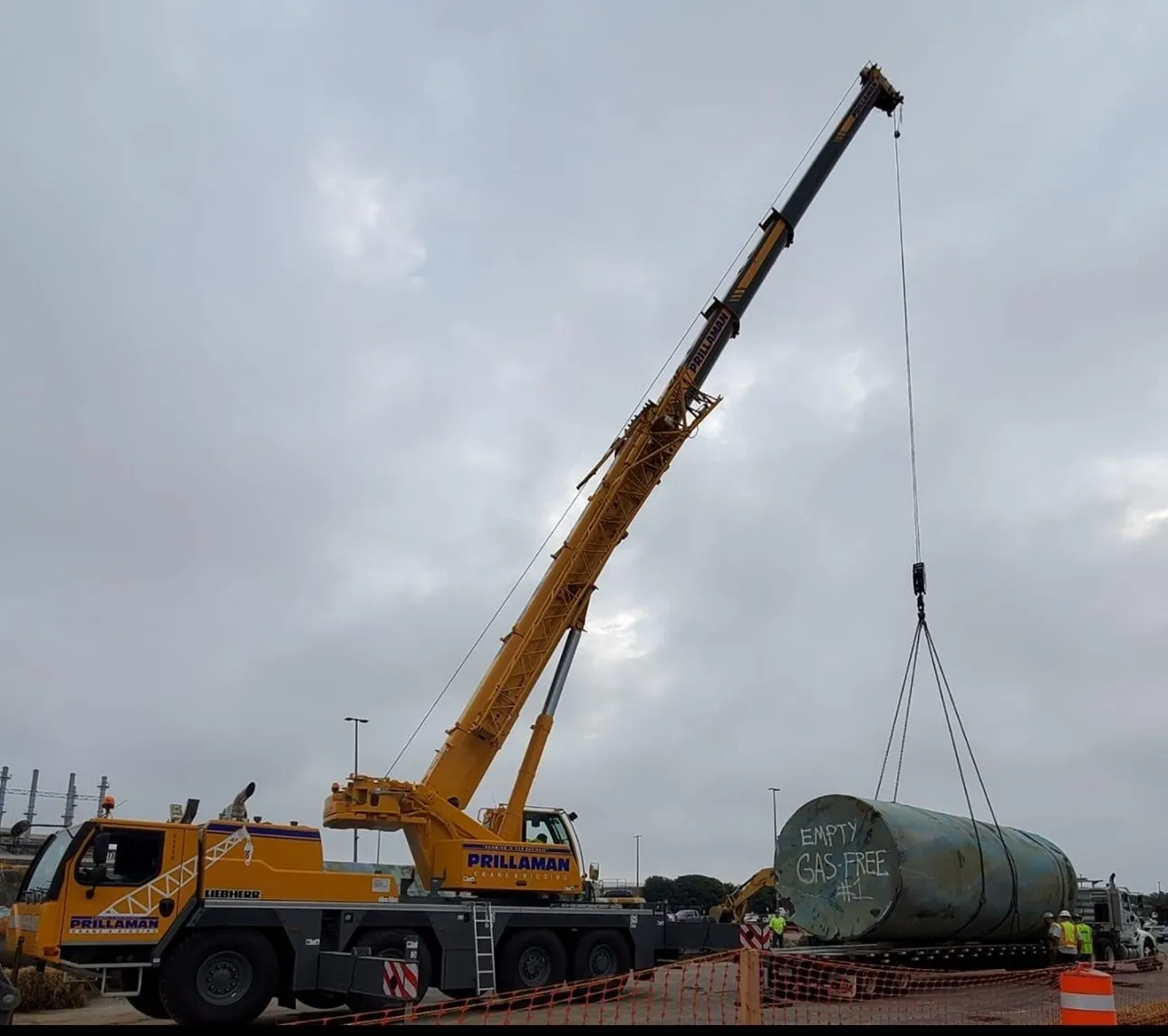 A crane is lifting a large metal tank.